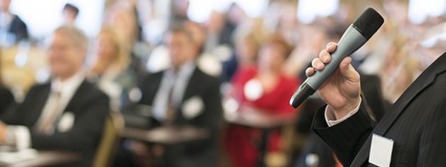 hand holding a microphone in front of an audiance