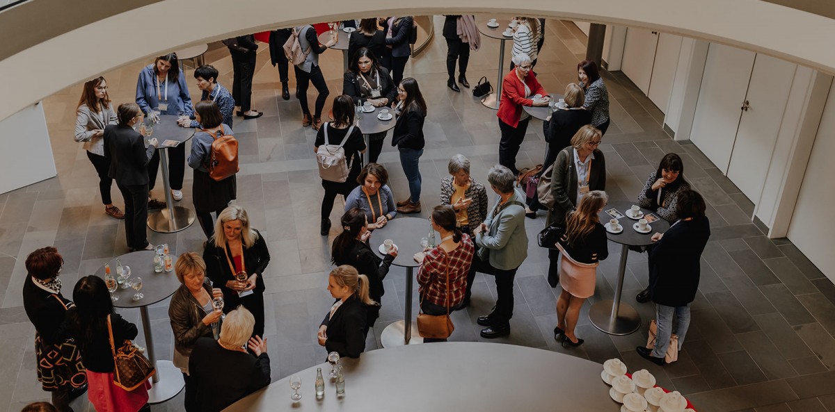 Frauen stehen an Stehtischen bei einem Netzwerktreffen